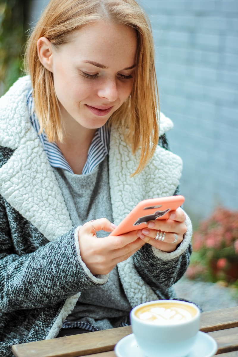 woman smiling while using her phone